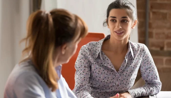 Two women dressed smart talking.
