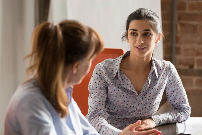 Two women dressed smart talking.