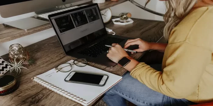 an image of someone working at their desk, with a laptop, notepad and iPhone.