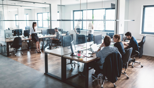 People working in an office, sitting at their desk and walking around.