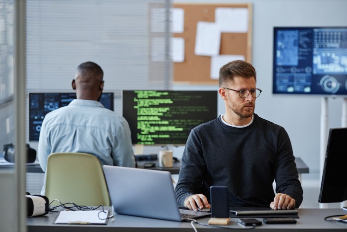 image of wo people sat at desks working at IT company